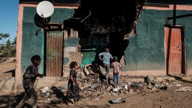 Niños juegan frente a una casa que resultó dañada durante los enfrentamientos que estallaron en la región de Tigray en Etiopía, en la aldea de Bisober, el 9 de diciembre de 2020.